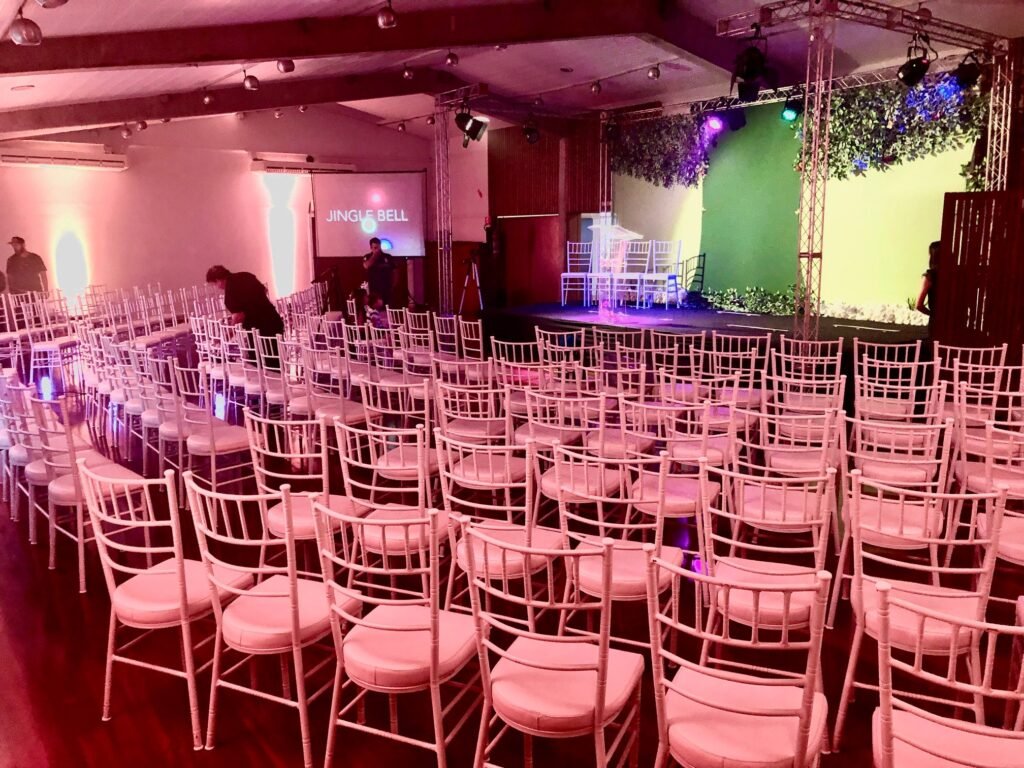 Salão com cadeiras brancas organizadas para um evento